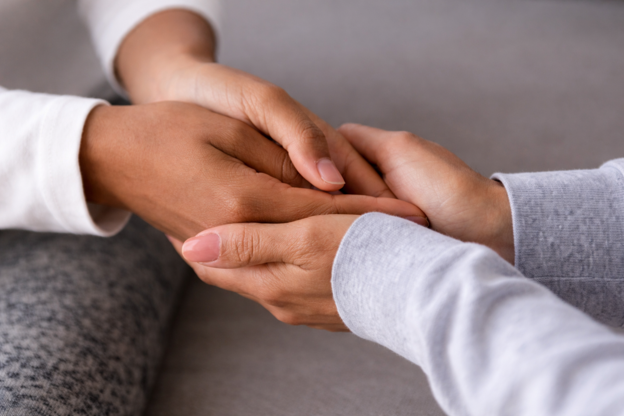 Close-up of hands holding in support, representing care, therapy, and human connection